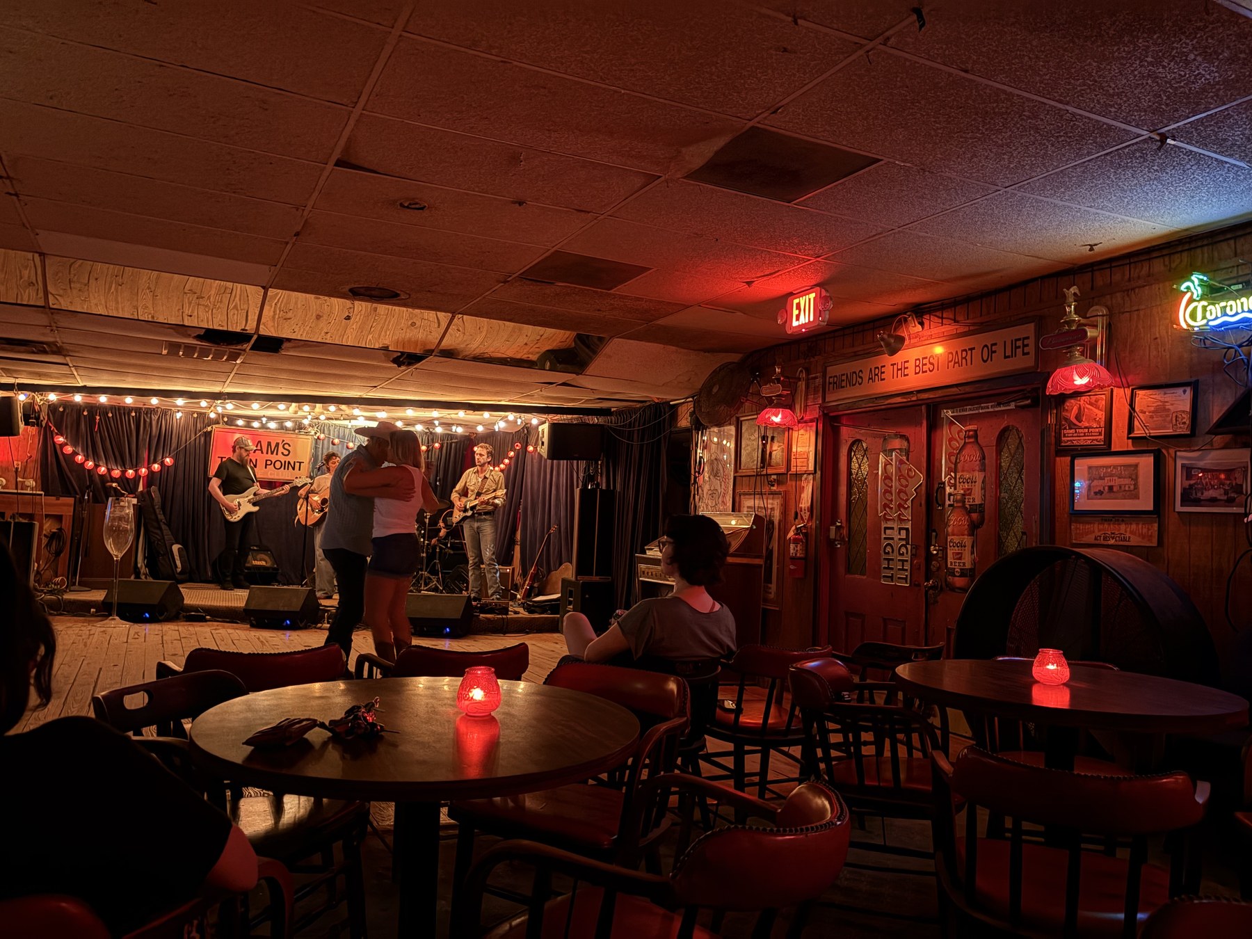 Wide shot of Sam's Town Point: band on stage and a woman watching from a table.