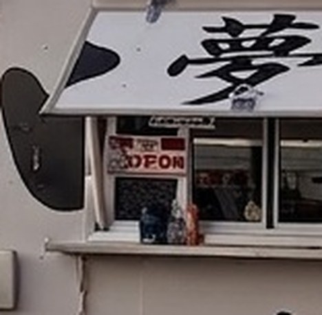 The same crop straight from the image model: the sign now reads garbled letters, and the painted character has lost its strokes.